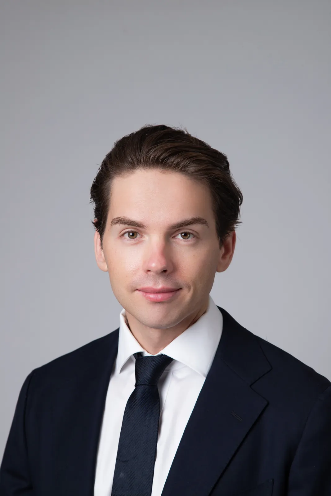 Retrato corporativo de homem jovem com terno azul-marinho e gravata