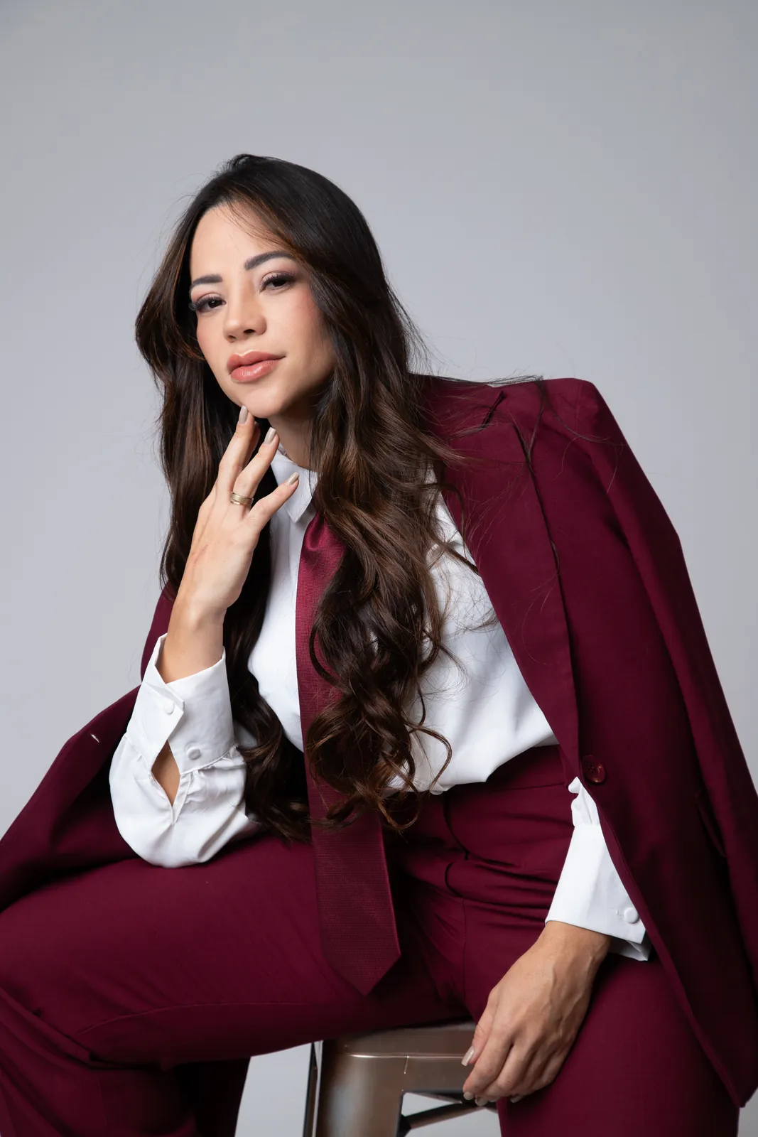 Retrato de marca pessoal de mulher com terno bordô sentada em banqueta